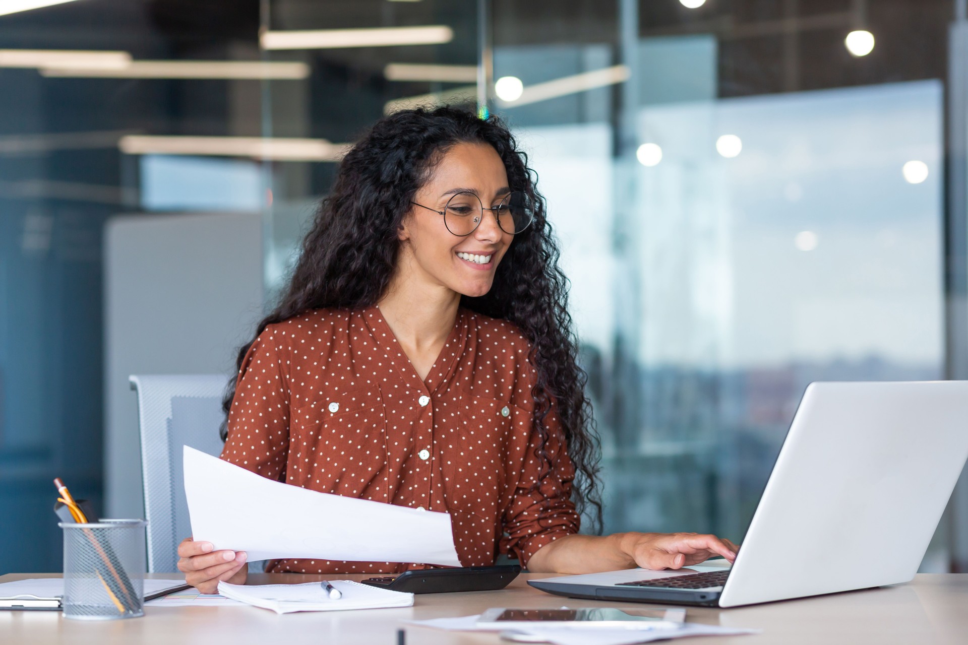 Young latin american businesswoman working inside office with documents and laptop, worker paperwork calculates financial indicators smiling and happy with success and results of achievement and work Young latin american businesswoman working inside office with documents and laptop, worker paperwork calculates financial indicators smiling and happy with success and results of achievement and work